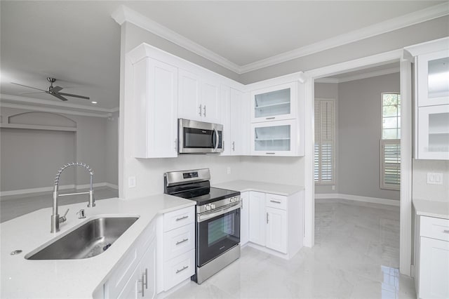 kitchen with appliances with stainless steel finishes, white cabinetry, crown molding, ceiling fan, and sink