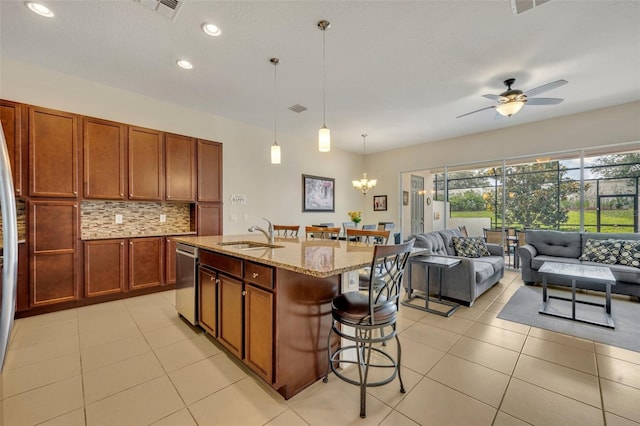 kitchen with light stone counters, a sink, open floor plan, a kitchen breakfast bar, and tasteful backsplash