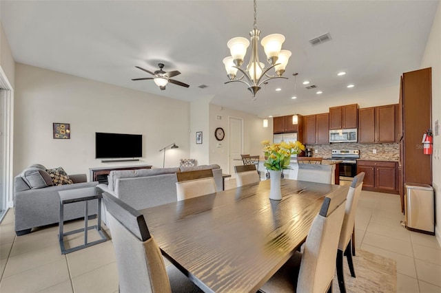 tiled dining space with ceiling fan with notable chandelier and a fireplace