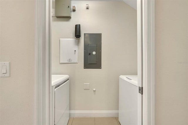 laundry area with electric panel, washing machine and dryer, and light tile patterned floors