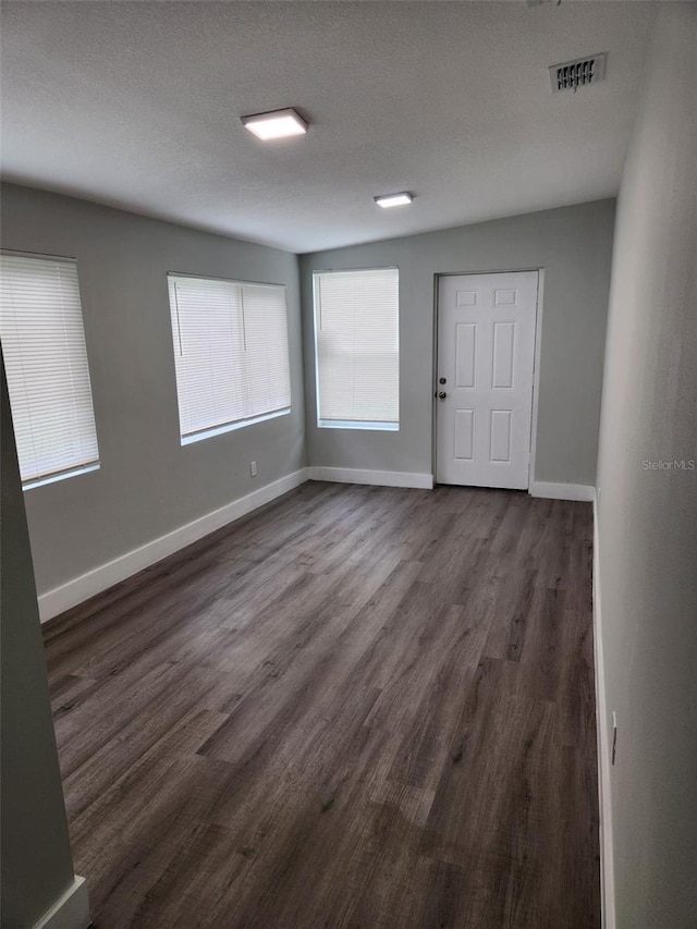 spare room featuring a textured ceiling and dark hardwood / wood-style floors