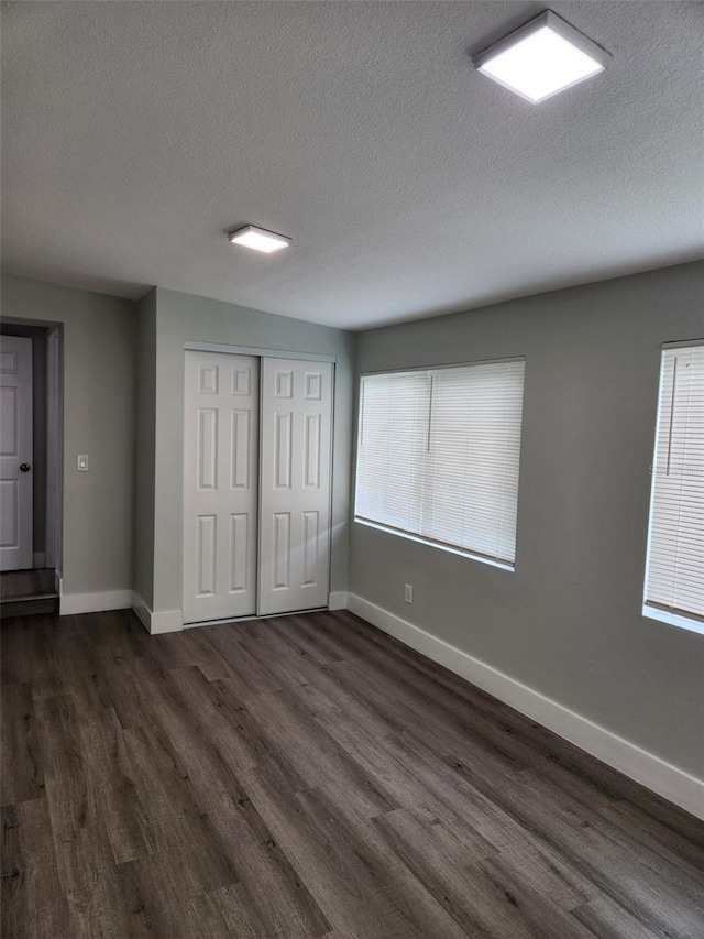 empty room with dark wood-type flooring and a textured ceiling