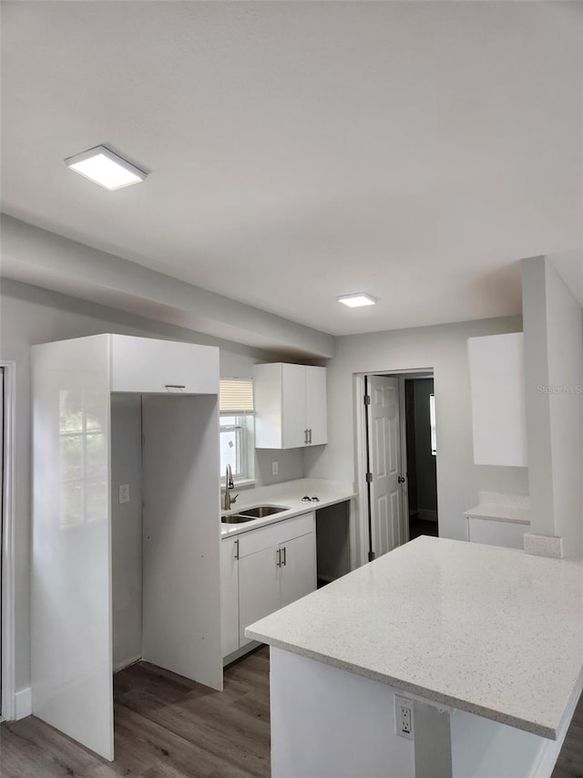 kitchen with white cabinetry, dark hardwood / wood-style flooring, sink, and light stone countertops