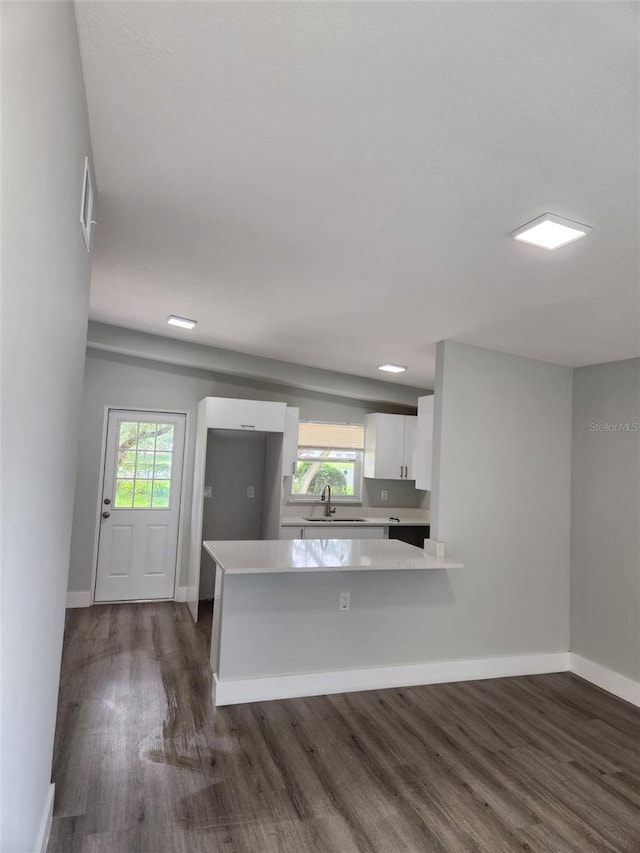 kitchen with white cabinets, a wealth of natural light, dark hardwood / wood-style floors, and kitchen peninsula