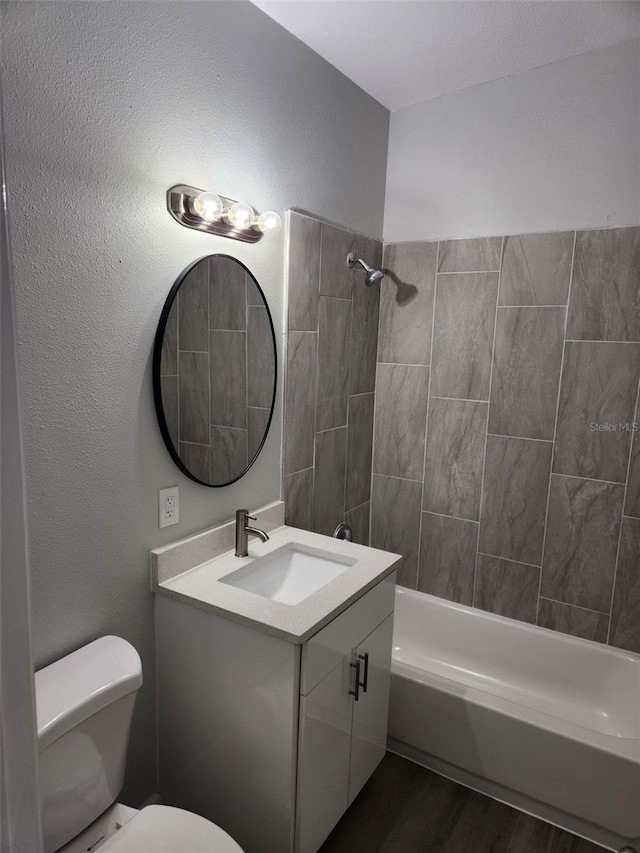 full bathroom with tiled shower / bath combo, vanity, toilet, and hardwood / wood-style floors