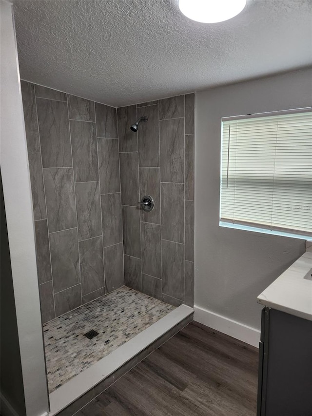 bathroom featuring vanity, a textured ceiling, hardwood / wood-style floors, and tiled shower