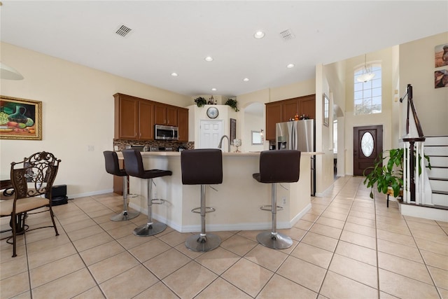 kitchen with a kitchen island with sink, stainless steel appliances, tasteful backsplash, and a breakfast bar area