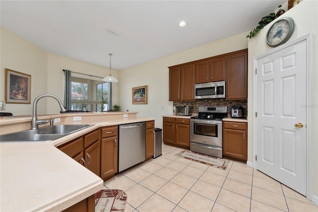 kitchen with pendant lighting, stainless steel appliances, light tile patterned flooring, and sink