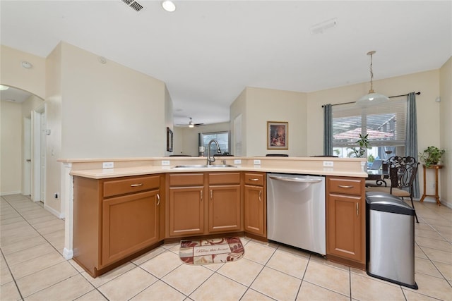 kitchen featuring a kitchen island with sink, dishwasher, sink, hanging light fixtures, and light tile patterned flooring