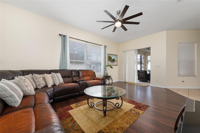 living room featuring dark wood-type flooring, ceiling fan, and a wealth of natural light