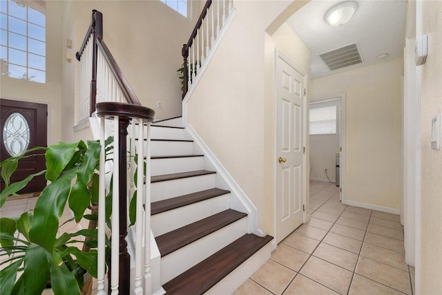 stairs with a high ceiling and tile patterned flooring