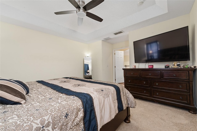 carpeted bedroom with a raised ceiling and ceiling fan