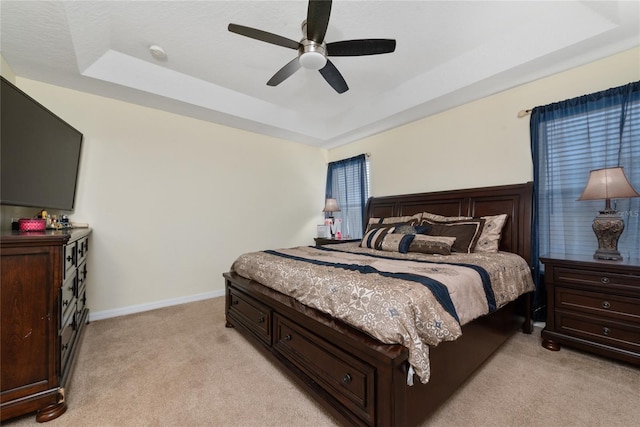 carpeted bedroom featuring a tray ceiling and ceiling fan