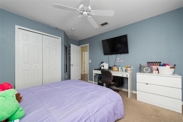 carpeted bedroom with a textured ceiling, ceiling fan, and a closet