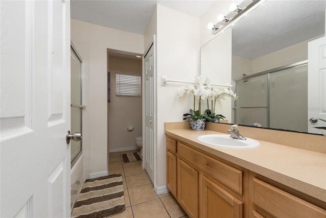 full bathroom featuring toilet, tile patterned floors, vanity, a textured ceiling, and enclosed tub / shower combo