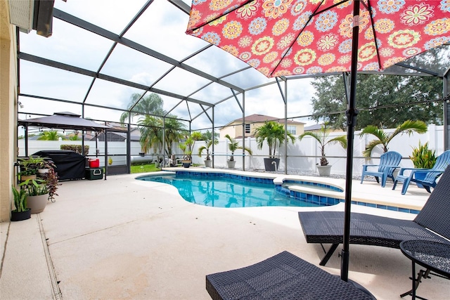 view of pool with glass enclosure, an in ground hot tub, and a patio