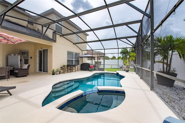 view of pool featuring glass enclosure, an in ground hot tub, and a patio