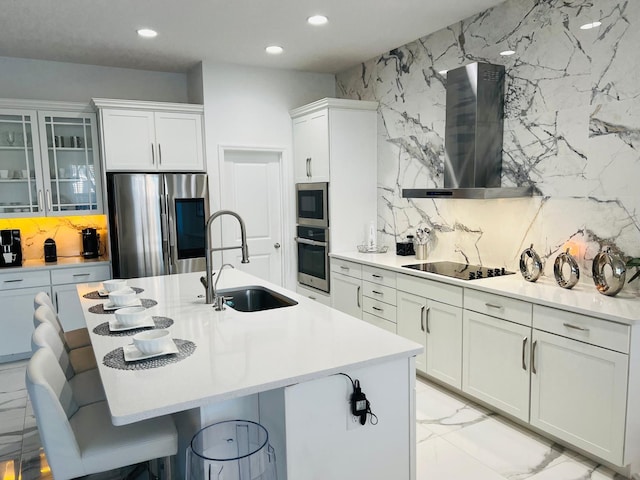 kitchen with white cabinetry, a kitchen bar, stainless steel appliances, sink, and wall chimney range hood