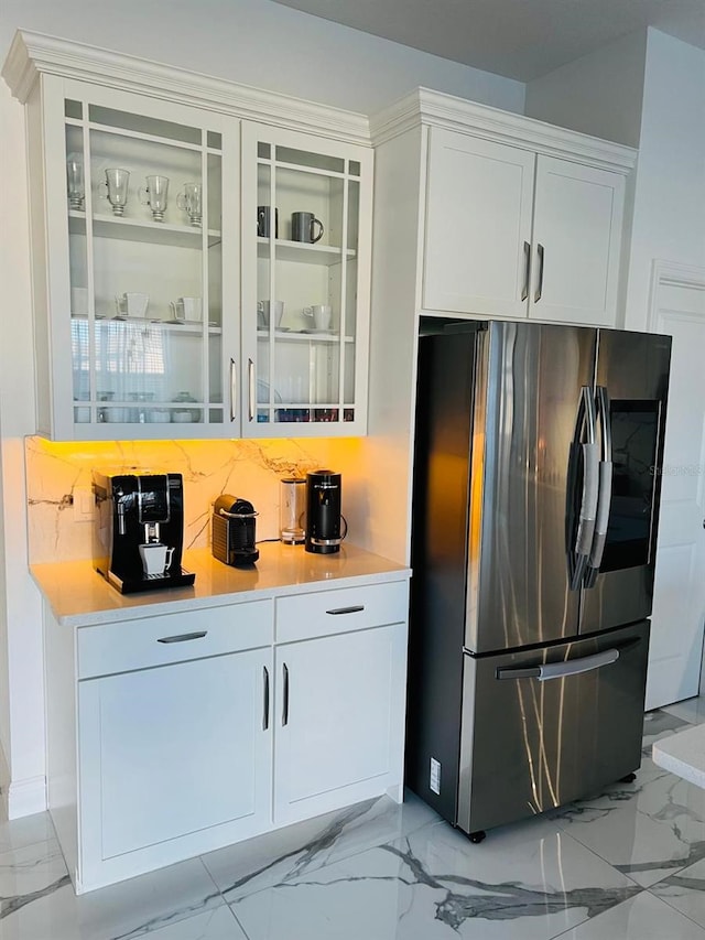 interior space featuring tasteful backsplash, stainless steel refrigerator, and white cabinets