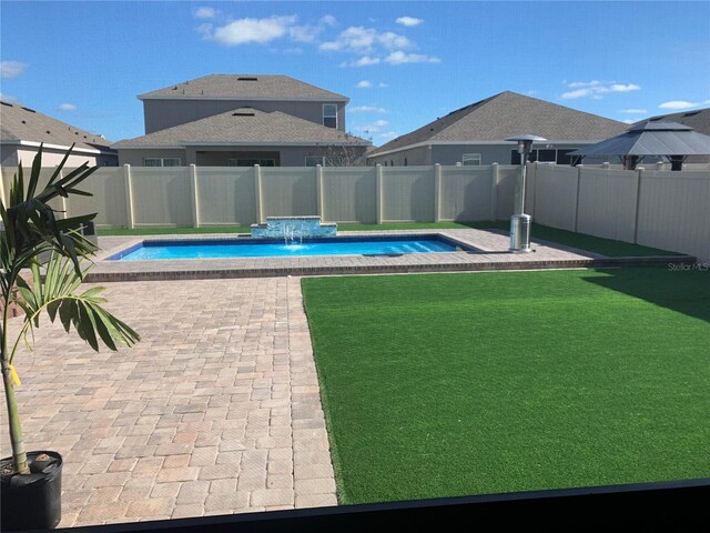 view of swimming pool with pool water feature, a patio, and a lawn