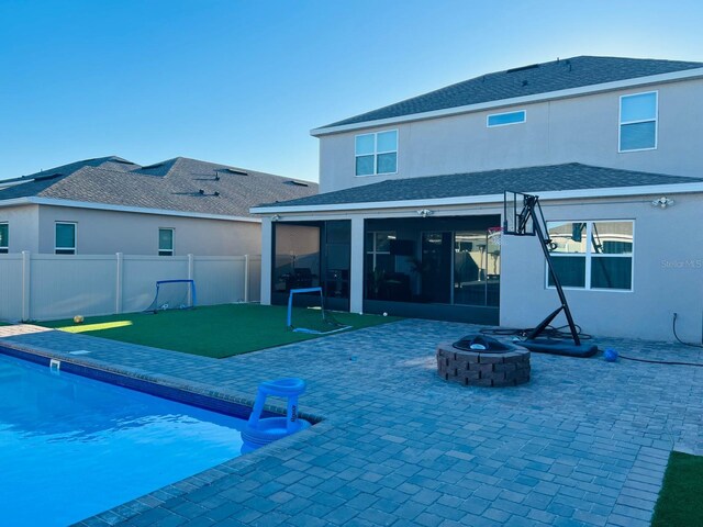 back of property with a fenced in pool, a patio area, and an outdoor fire pit