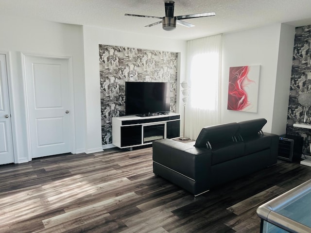 living room with dark wood-type flooring, ceiling fan, and a textured ceiling