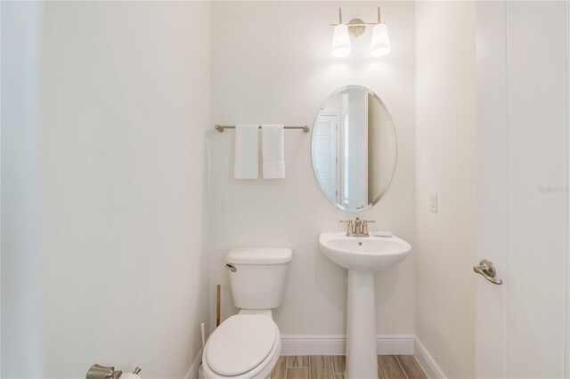 bathroom featuring toilet, wood-type flooring, and sink