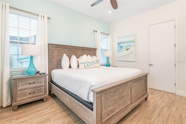 bedroom with ceiling fan, multiple windows, and light hardwood / wood-style floors