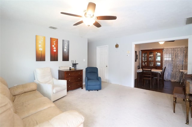 carpeted living area with visible vents and ceiling fan