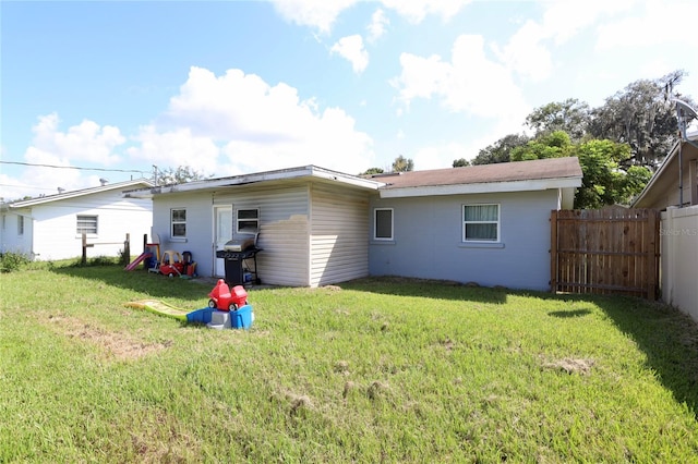 rear view of property featuring a yard and fence