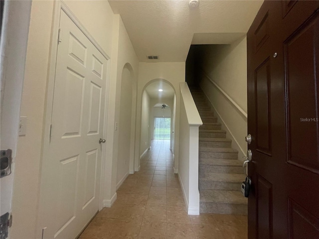 hallway with a textured ceiling and light tile patterned floors