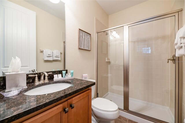 bathroom featuring tile patterned floors, walk in shower, toilet, and vanity