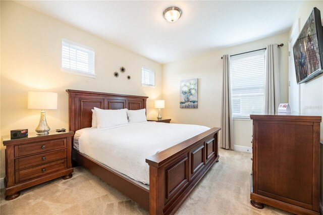 bedroom with light carpet and multiple windows