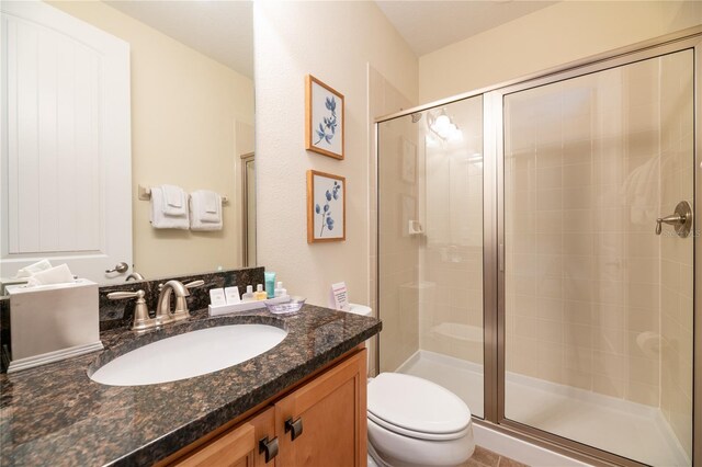 bathroom featuring vanity, toilet, and a shower with door