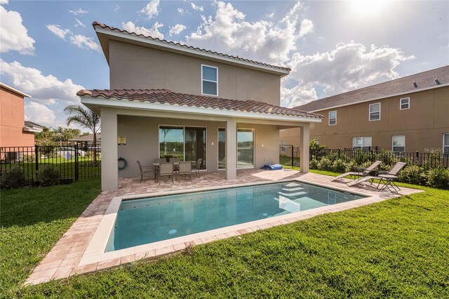 rear view of house with a fenced in pool, a yard, and a patio