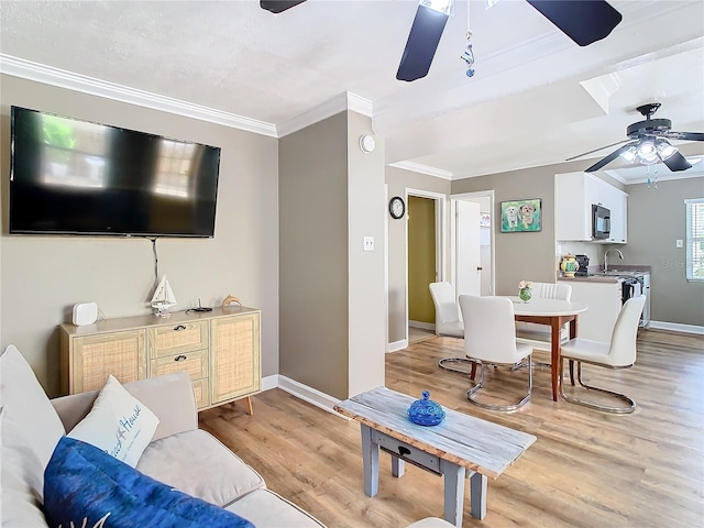 living room featuring ornamental molding, sink, ceiling fan, and light hardwood / wood-style flooring