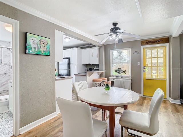 dining space with a textured ceiling, crown molding, ceiling fan, and light hardwood / wood-style flooring