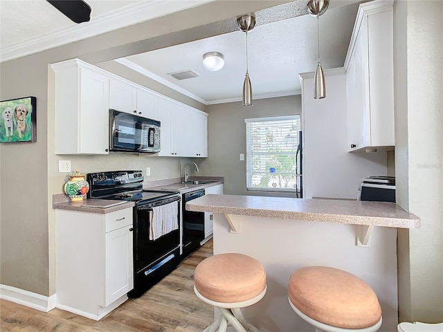 kitchen featuring black appliances, a kitchen bar, kitchen peninsula, and white cabinets