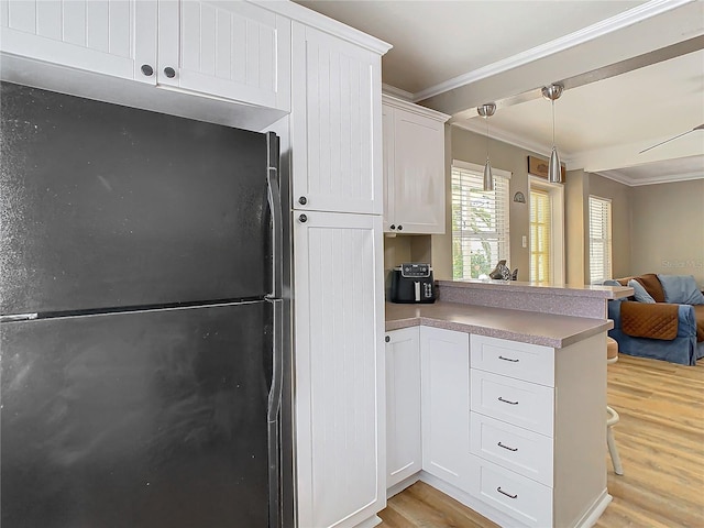 kitchen featuring black fridge, decorative light fixtures, white cabinetry, light wood-type flooring, and crown molding