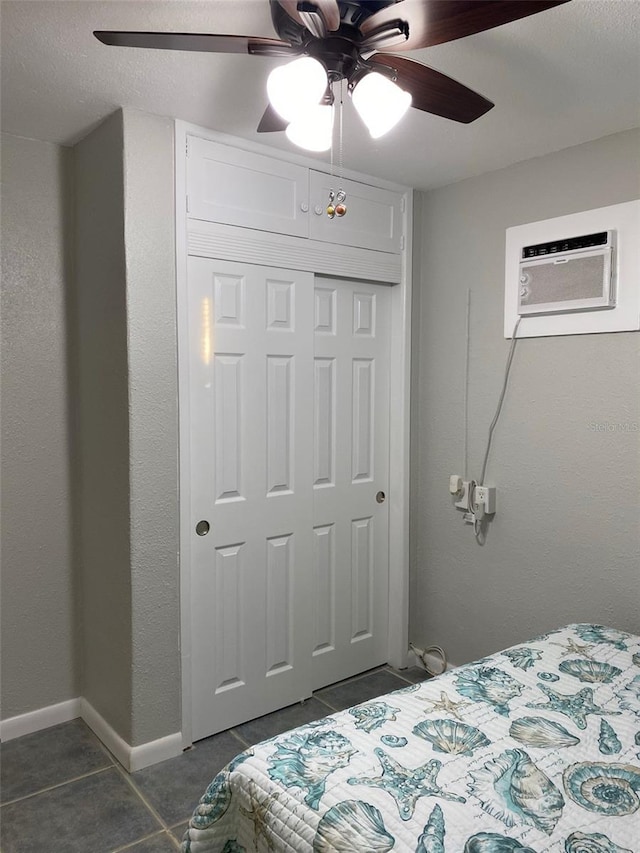 bedroom featuring dark tile patterned flooring, a closet, a textured ceiling, ceiling fan, and a wall unit AC