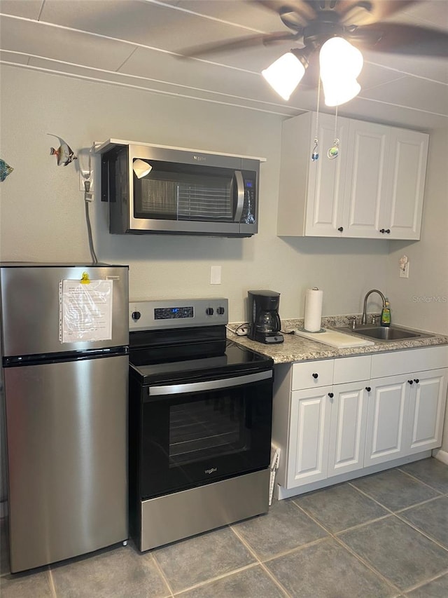 kitchen with ceiling fan, white cabinets, sink, appliances with stainless steel finishes, and tile patterned flooring