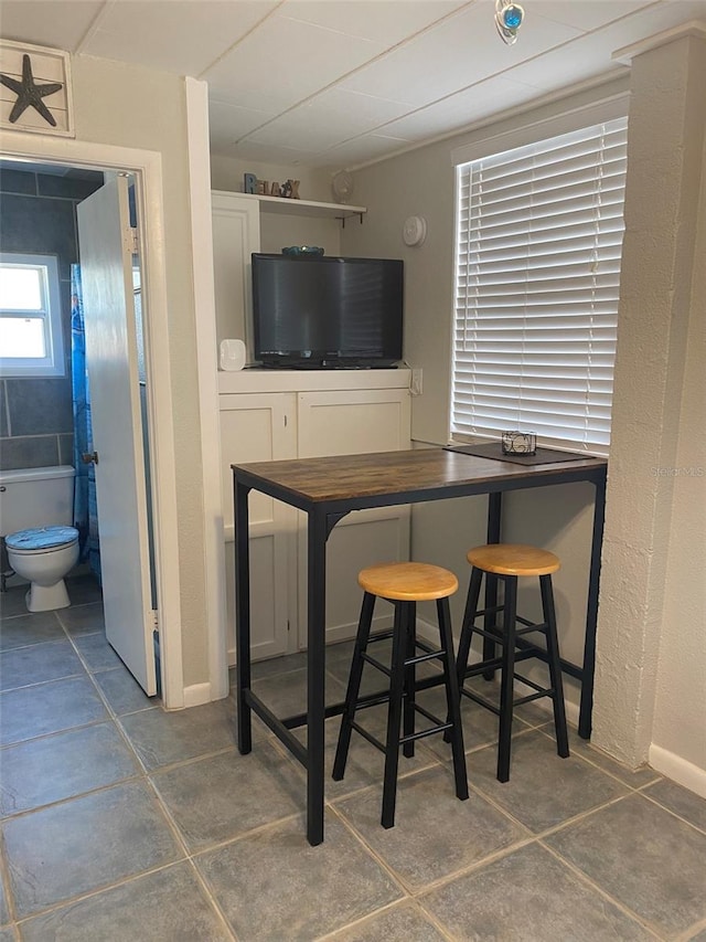 bar featuring dark tile patterned flooring and white cabinets