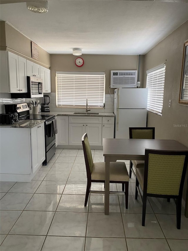 kitchen with sink, white cabinets, appliances with stainless steel finishes, light tile patterned floors, and a wall mounted air conditioner