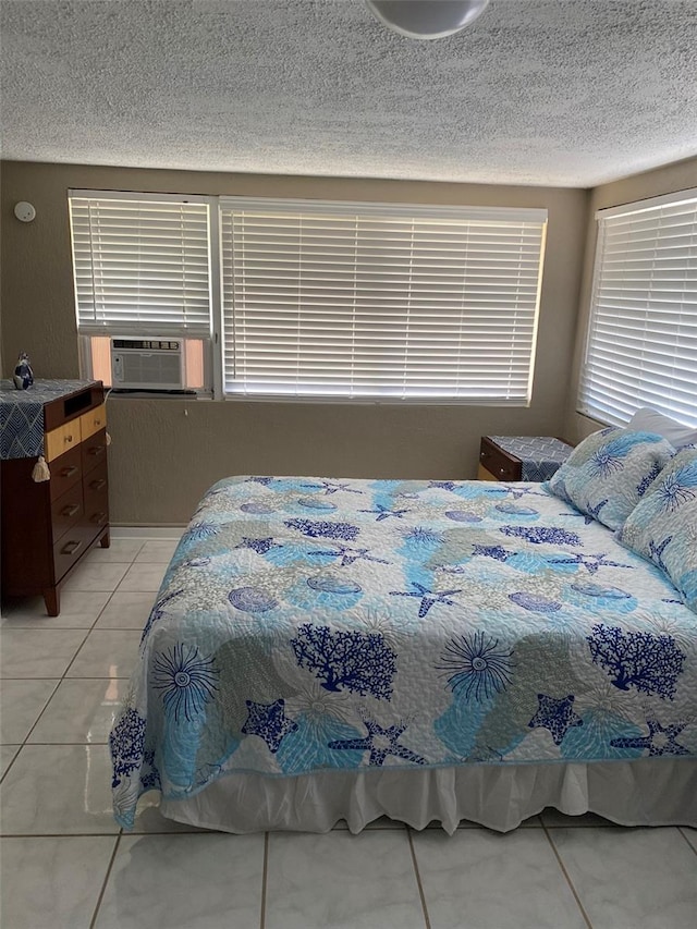 bedroom featuring cooling unit, a textured ceiling, and light tile patterned flooring