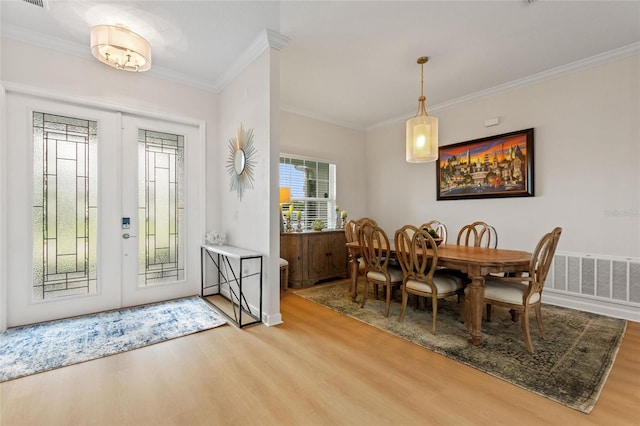 dining room with light hardwood / wood-style floors and crown molding