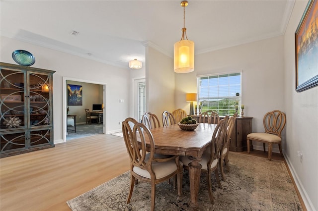 dining space featuring wood-type flooring and ornamental molding