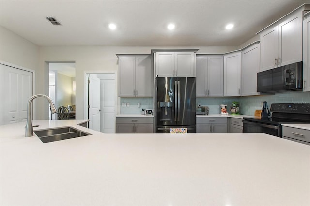 kitchen featuring gray cabinets, black appliances, backsplash, and sink