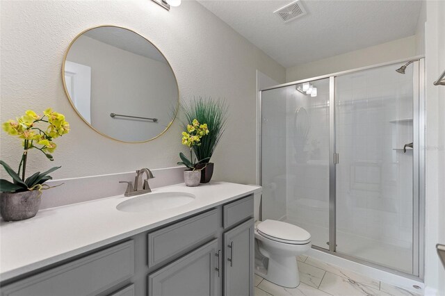 bathroom featuring a shower with shower door, toilet, a textured ceiling, and vanity