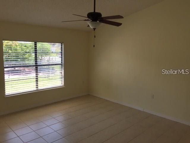 tiled empty room with ceiling fan