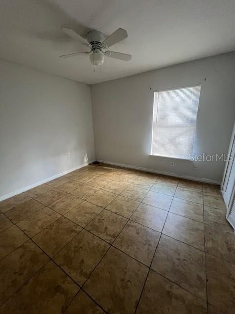 tiled spare room featuring ceiling fan